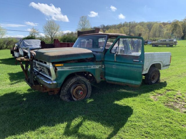1976 Ford Truck plow setting out in green pastures.